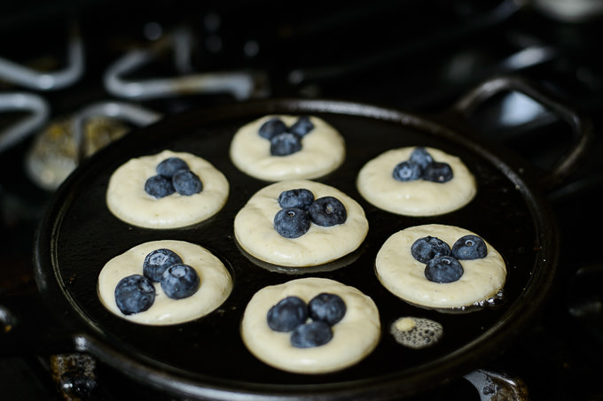 Danish style aebleskiver apple pancakes or pancake puffs served in a cast  iron pan on white rustic boards. - Live Free Creative Co